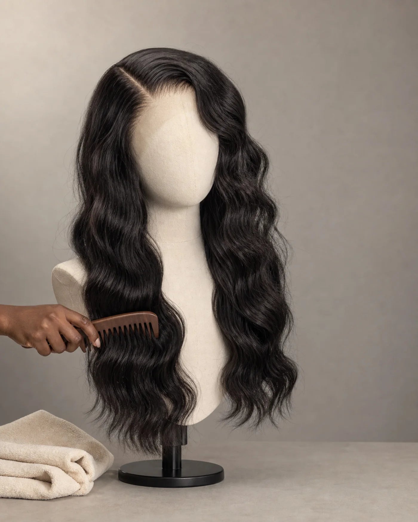 Long natural-black waves rest on a wig stand after gentle care with a wide-tooth comb nearby.