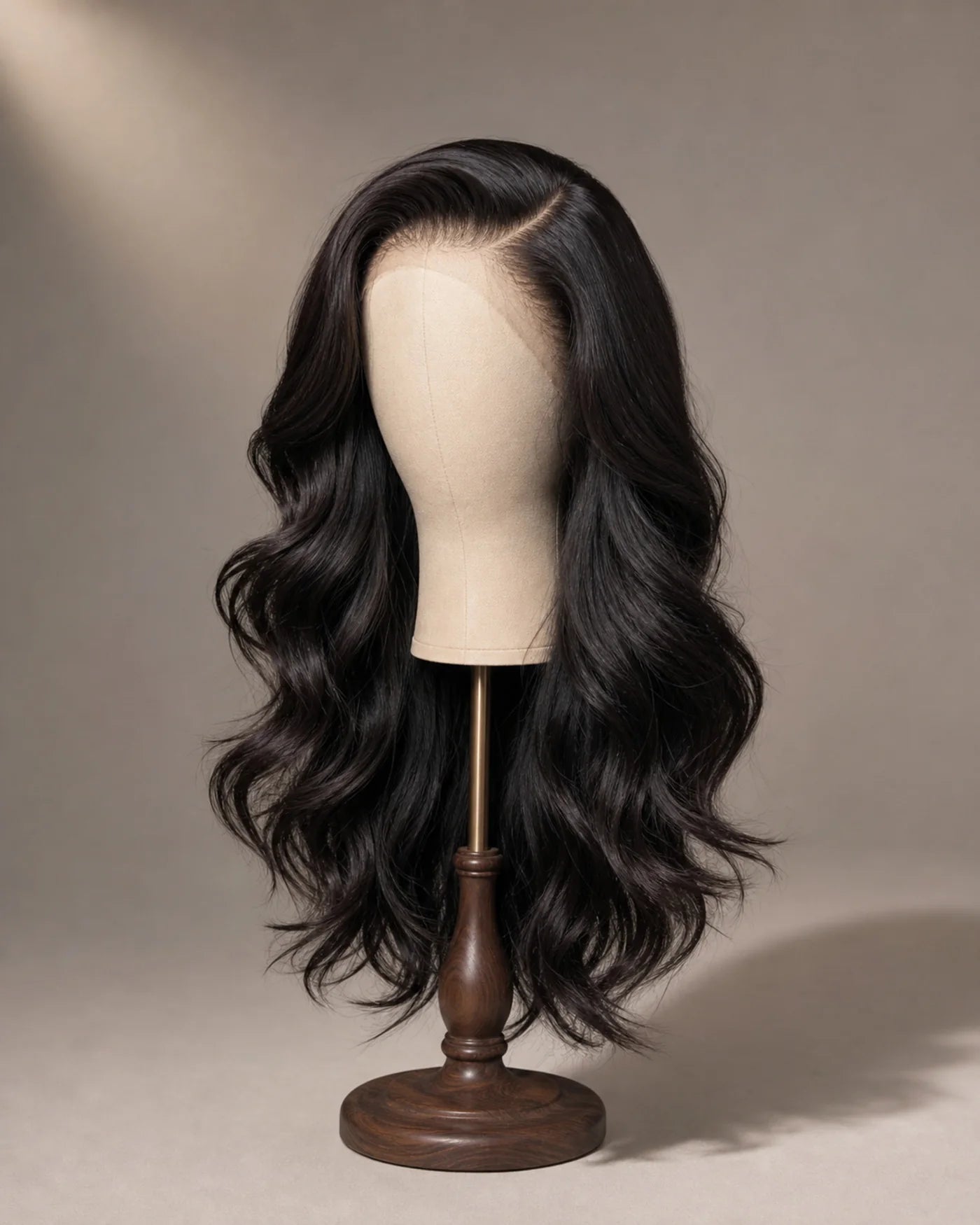 Finished long natural-black waves are displayed in a smooth polished starting style on a wig stand.